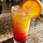 Sunrise Sparkler Mocktail – A vibrant layered drink featuring orange juice and grenadine for a sunrise effect.