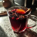 A festive mug of Christmas Mulled Cranberry Cider, garnished with cranberries, star anise, an orange slice, and a cinnamon stick.