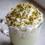 A festive Christmas Pistachio Hot White Chocolate topped with whipped cream and chopped pistachios.
