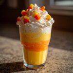A festive Halloween Candy Corn Milkshake with three distinct layers and whipped cream topped with candy corn.
