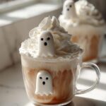 A festive Halloween Ghostly White Hot Chocolate topped with whipped cream and cute ghost marshmallows.