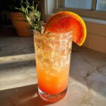 A refreshing New Year’s Eve Citrus Sparkler Mocktail with grapefruit slice and rosemary garnish.
