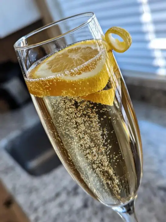 A bubbly New Year's Eve French 75 cocktail in a champagne flute, garnished with lemon slices and a twist.