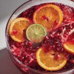 Close-up of New Year’s Eve Sparkling Pomegranate Punch with orange slices, lime, and pomegranate seeds.
