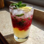 A refreshing New Year's Eve Sparkling Raspberry Lemonade with raspberries, mint, and a lemon slice.