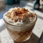 A close-up of a Thanksgiving Cinnamon Maple Latte topped with whipped cream and a sprinkle of cinnamon.