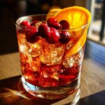 A refreshing Thanksgiving Cranberry Bourbon Smash cocktail with fresh cranberries and an orange slice garnish.