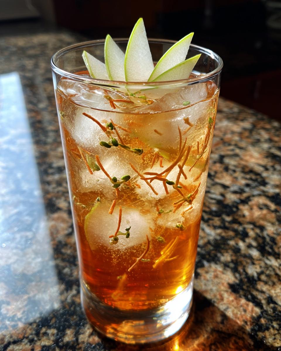 A refreshing Thanksgiving Ginger Pear Spritz cocktail with ice, garnished with pear slices and herbs.
