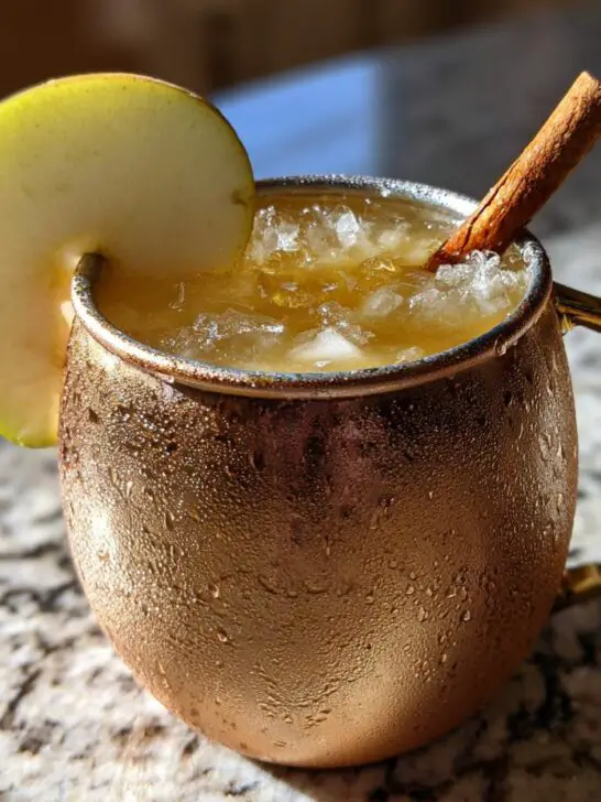 A refreshing Thanksgiving Spiced Pear Mule in a copper mug, garnished with a pear slice and cinnamon stick.