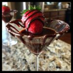 A close-up of a Valentine&rsquo;s Day Chocolate-Covered Strawberry Martini, garnished with a fresh strawberry drizzled with chocolate.