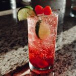 A refreshing Valentine’s Day Love Potion Mocktail with ice, cherries, and lime slices.