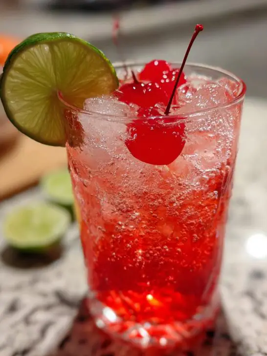 A refreshing Valentine’s Day Love Potion Mocktail with cherries and lime on ice.
