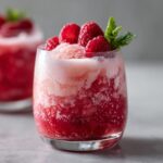 Close-up of a Valentine's Day Raspberry Champagne Float garnished with fresh raspberries and mint.