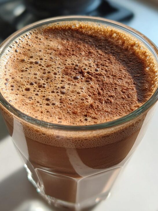 Close-up of a frothy Cacao Almond Energy Shake in a glass, ready to drink.