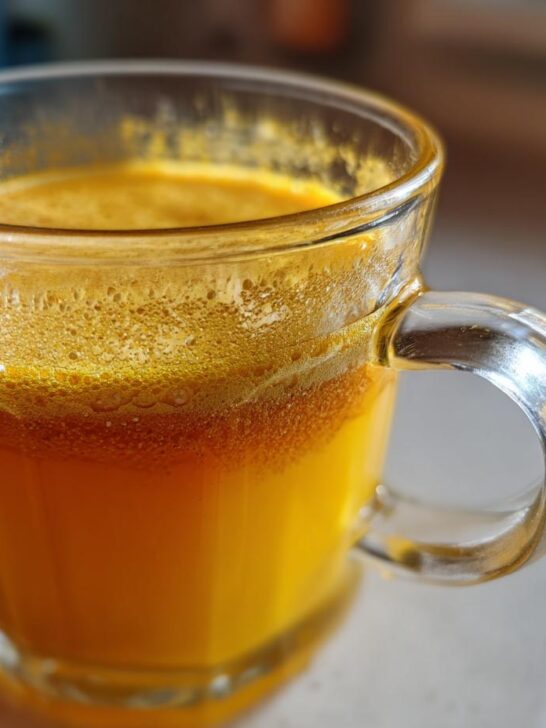 Close-up of a vibrant orange Ginger Lemon Honey Energy Shot in a glass mug.