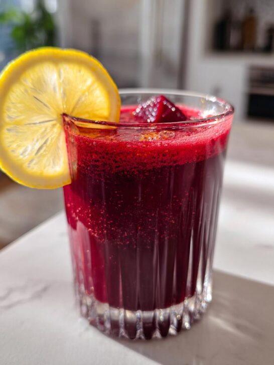 A vibrant Ginger Lemon Honey Energy Shot made with beetroot, garnished with a lemon slice and served in a glass.