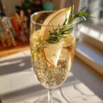 A refreshing Ginger Pear Champagne Cocktail garnished with pear slices and fresh rosemary sprigs.