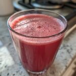 A glass of vibrant pink Kale Kiwi Energy Refresher drink with a frothy top.