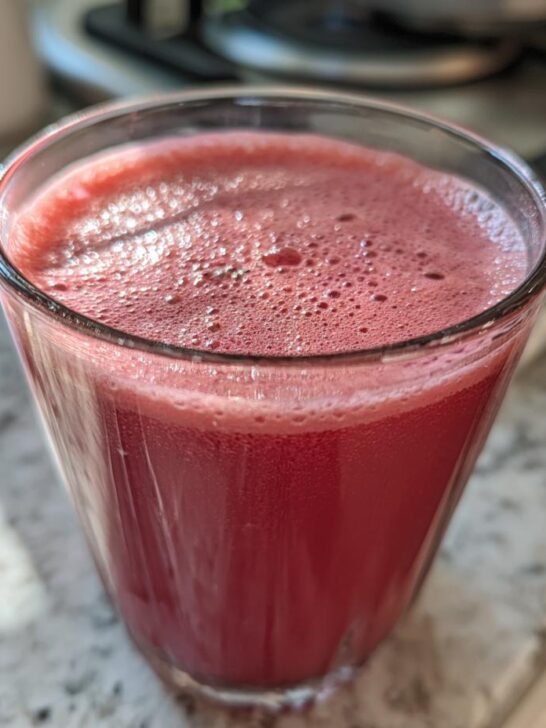 A glass of vibrant pink Kale Kiwi Energy Refresher drink with a frothy top.