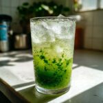 A tall glass filled with a vibrant green Kiwi Spinach Detox Mocktail, packed with ice and bubbly.