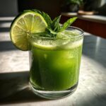 A vibrant green Matcha Coconut Rum Cooler cocktail garnished with a lime wheel and fresh mint leaves.