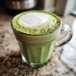 A close-up of a frothy Matcha Green Energy Latte in a clear glass mug, ready to be enjoyed.