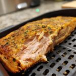 Close-up of a perfectly cooked Air Fryer Salmon fillet, showing its flaky texture and seasoned crust.