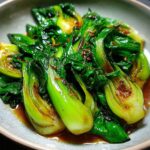 Close-up of a serving of tender Baby Bok Choy Recipe, glistening with a savory sauce and spices.