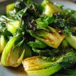 Close-up of a vibrant Baby Bok Choy Recipe, glistening with sauce and sprinkled with sesame seeds.