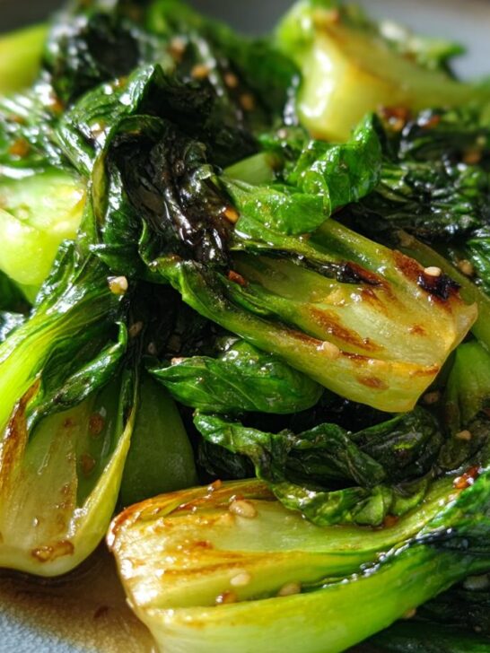 Close-up of a vibrant Baby Bok Choy Recipe, glistening with sauce and sprinkled with sesame seeds.