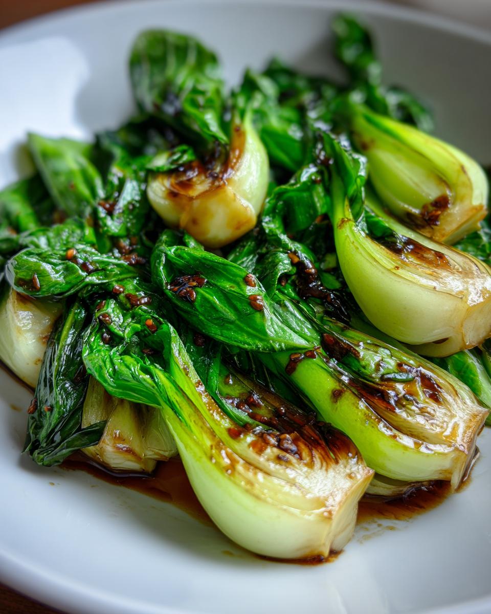 Close-up of a white plate filled with glistening, stir-fried Baby Bok Choy in a savory sauce.