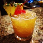 A refreshing Bartenders Best Nonalcoholic Cocktail with crushed ice, garnished with pineapple and cherries.