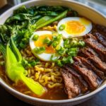 A close-up of a hearty bowl of Beef Ramen Recipe, featuring tender sliced beef, ramen noodles, bok choy, and a soft-boiled egg.