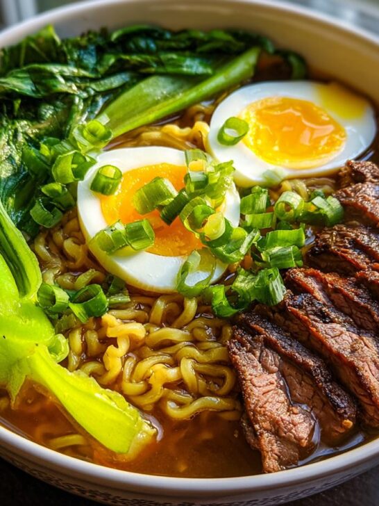 A close-up of a hearty bowl of Beef Ramen Recipe, featuring tender sliced beef, ramen noodles, bok choy, and a soft-boiled egg.