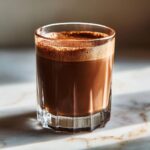 A close-up of a rich, frothy chocolate cocktail in a faceted glass, perfect for best chocolate cocktails.