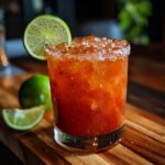 A refreshing red cocktail with ice, lime garnish, and a salt rim, perfect for Best Cocktails Super Bowl 2024.