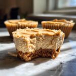 Close-up of a No Bake Peanut Butter Cheesecakes with a bite taken out, showing creamy filling and graham cracker crust.