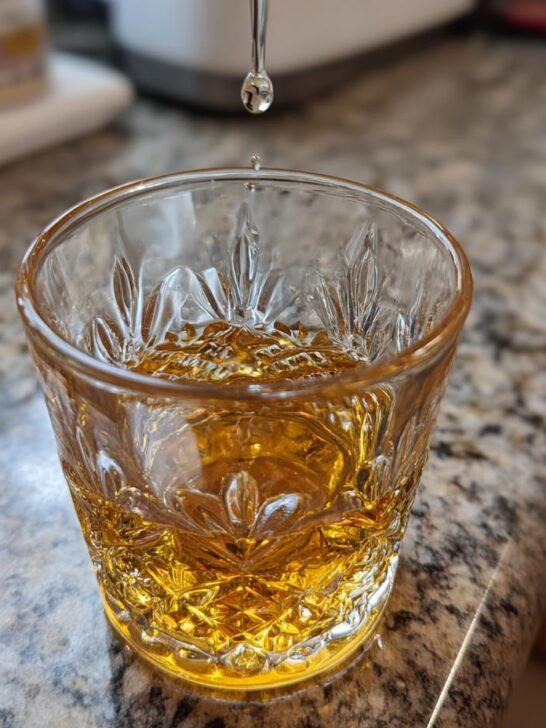 A drop of Bruichladdich Classic Laddie whisky falling into a crystal glass.