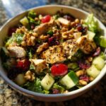 A bowl of Cherry Walnut Chicken Salad featuring grilled chicken, walnuts, dried cherries, cucumber, and lettuce.