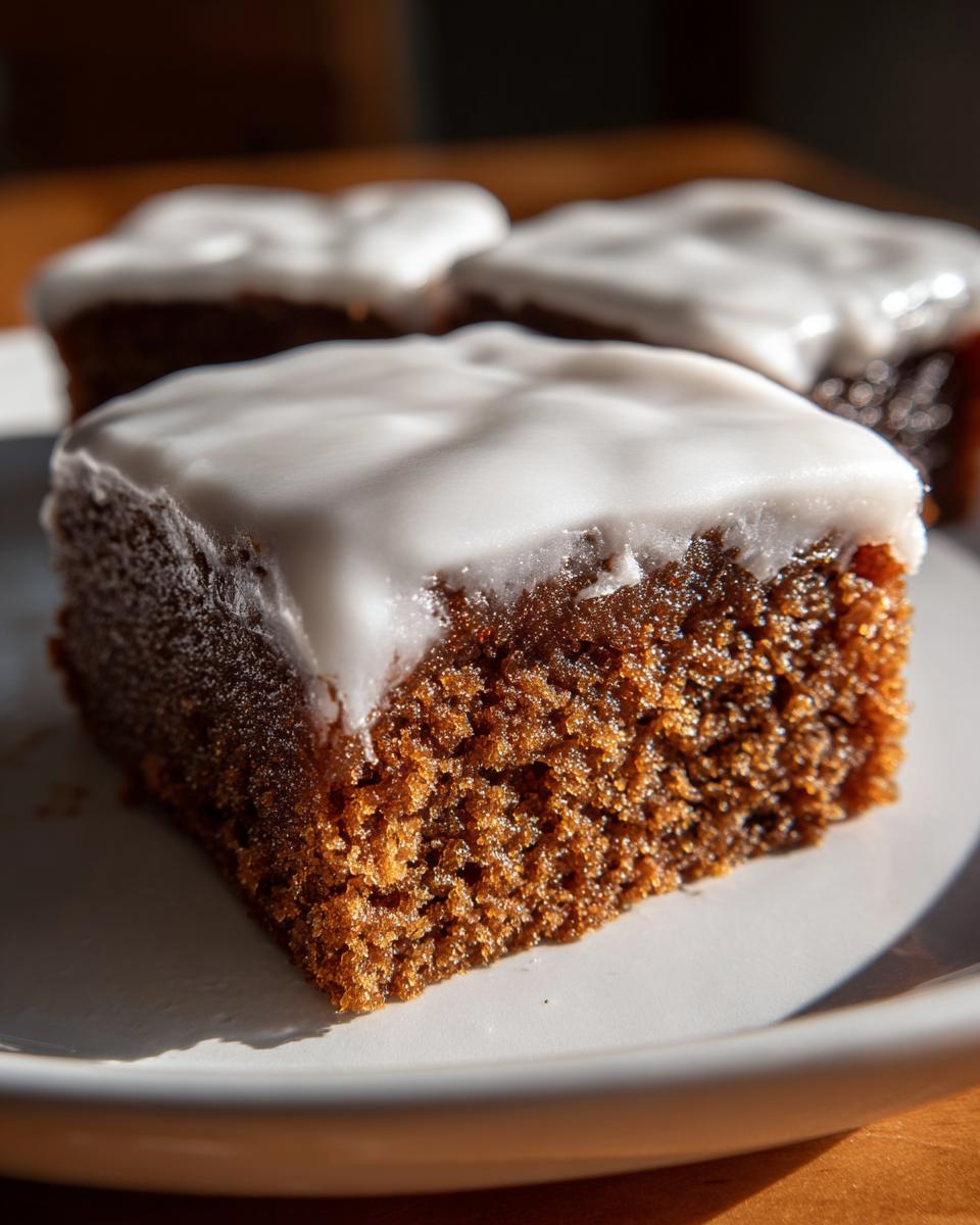 Close-up of a square Gingerbread Cookie Bars slice with a thick layer of white icing.
