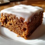 Close-up of a square slice of rich, dark Gingerbread Cookie Bars topped with thick white icing.