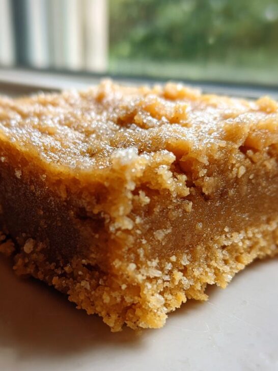 A close-up, macro shot of a thick, chewy square of Peanut Butter Cookie Bars with a crumbly base.
