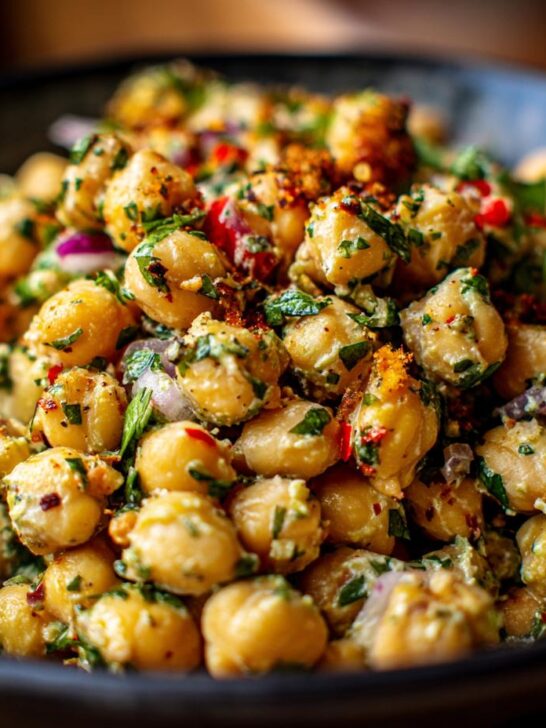 A close-up, vibrant bowl of Chickpea Salad, featuring chickpeas, red onion, fresh herbs, and a flavorful dressing.
