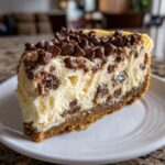 A rich slice of Chocolate Chip Cheesecake featuring a graham cracker crust and topped with mini chocolate chips.