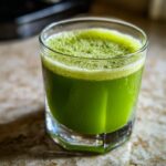 A glass of vibrant green Cucumber Ginger Lemon Detox Juice with a foamy top.