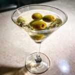 A classic Dirty Martini in a martini glass, garnished with three green olives.