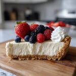 A slice of easy no bake cheesecake topped with fresh strawberries, blueberries, raspberries, blackberries, and whipped cream.