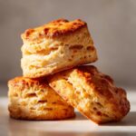 A stack of three golden-brown, flaky sweet potato biscuits with visible layers.