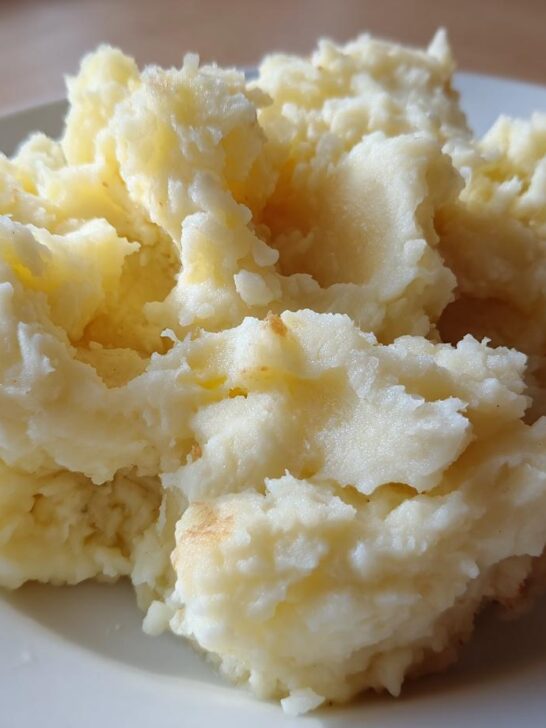 A close-up of a serving of fluffy mashed potatoes on a white plate, a perfect example of comforting potato recipes.