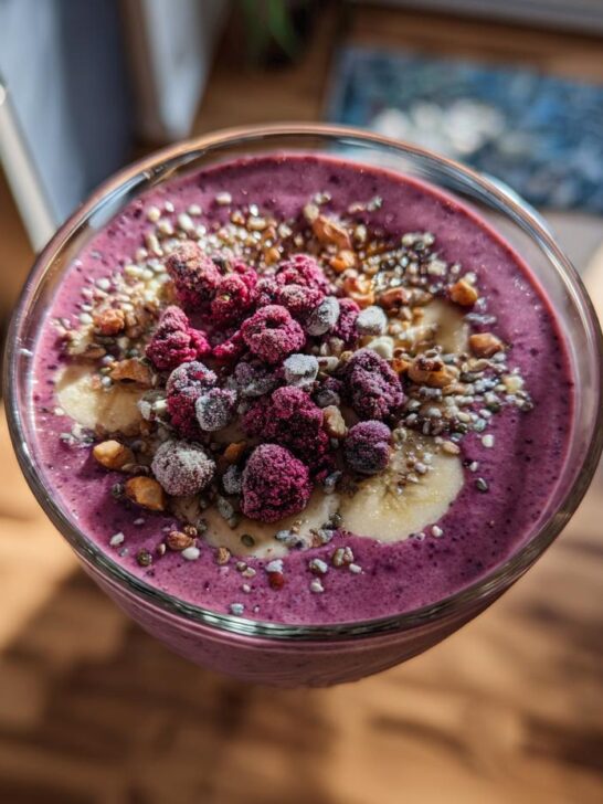 A vibrant purple smoothie bowl topped with frozen berries, banana slices, and seeds, showcasing one of 10 Irresistible Frozen Banana Recipes.